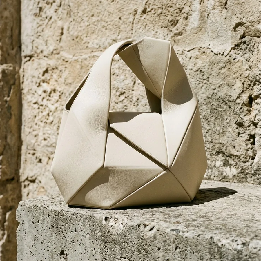 Sculptural cream calfskin handbag on raw concrete and sun-bleached stone